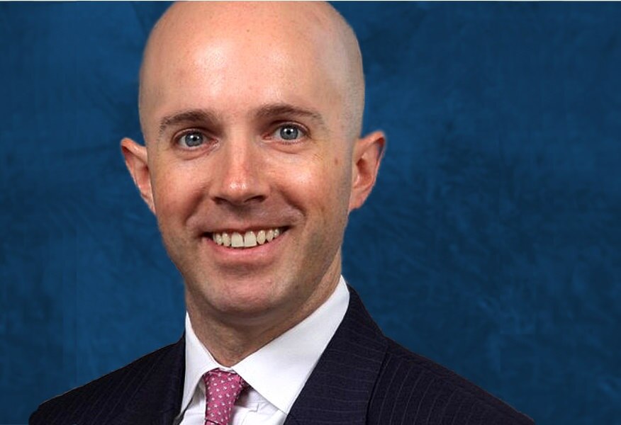 A photo of a bald man wearing a business suit.