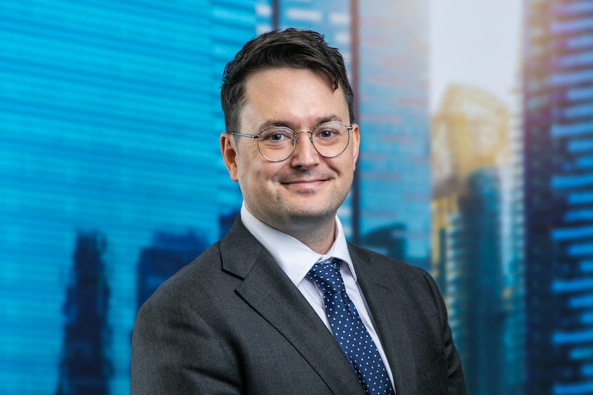 a man with short hair wearing a suit and glasses.