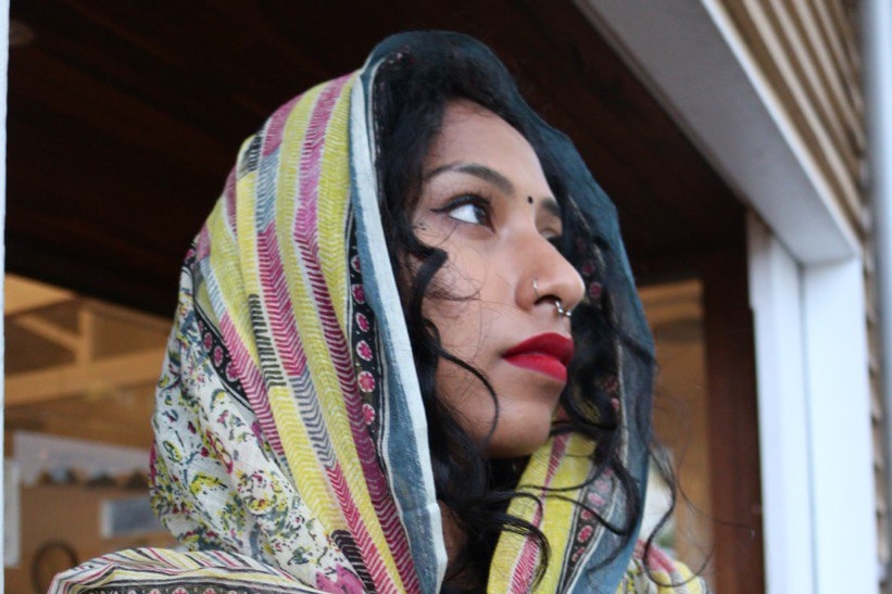 A woman wearing a colourful garment over her head.