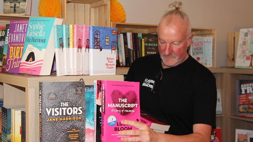 A man arranges books in a store.