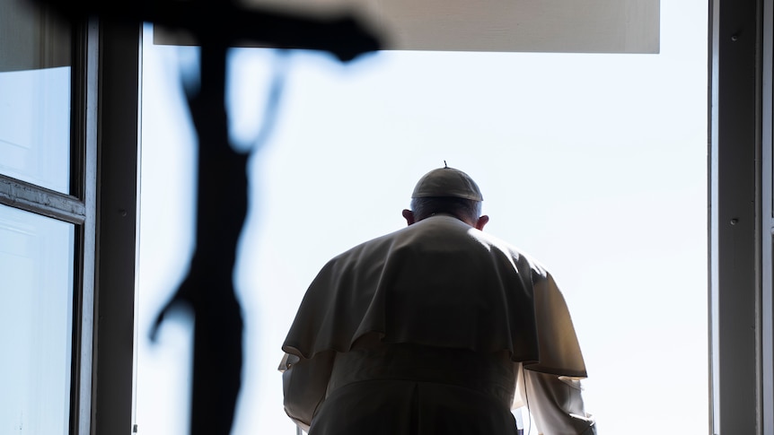 Pope Francis standing before an open window