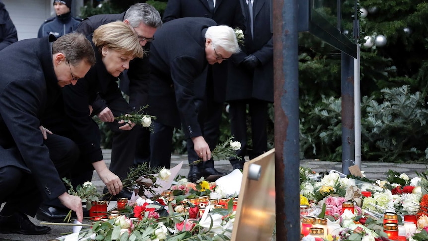 German Chancellor Angela Merkel joins other dignitaries laying flowers at a memorial.