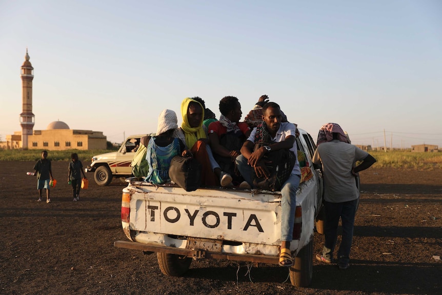 Ethiopian refugees sit on the back of a ute in front of a mosque in Sudan