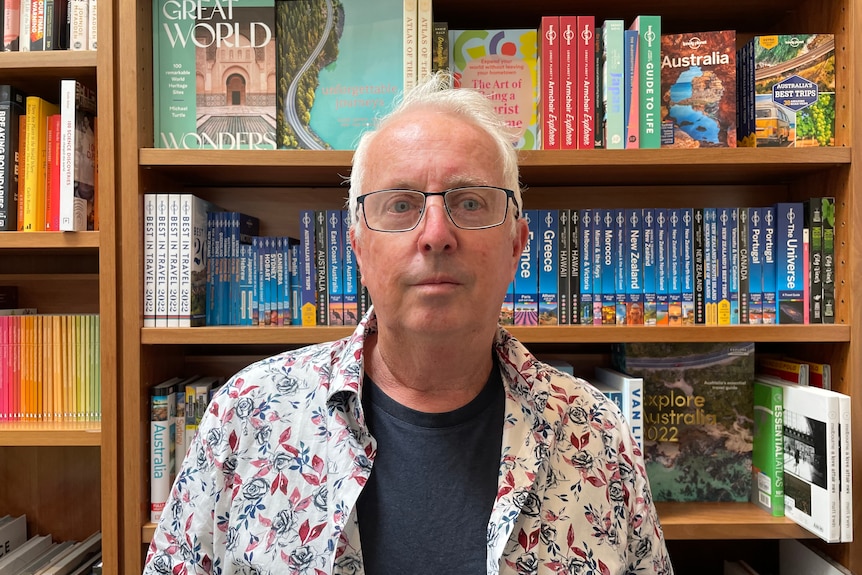 Man stands in front of book shelf 
