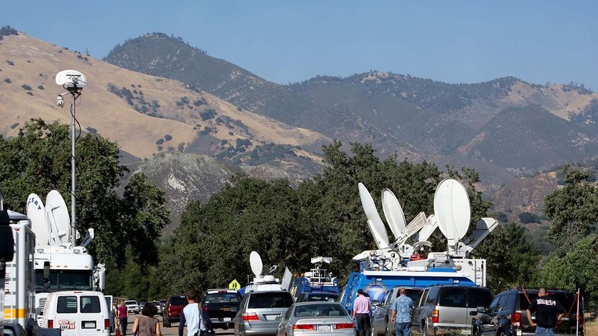 Television news trucks line the road outside the front gates of Neverland Ranch