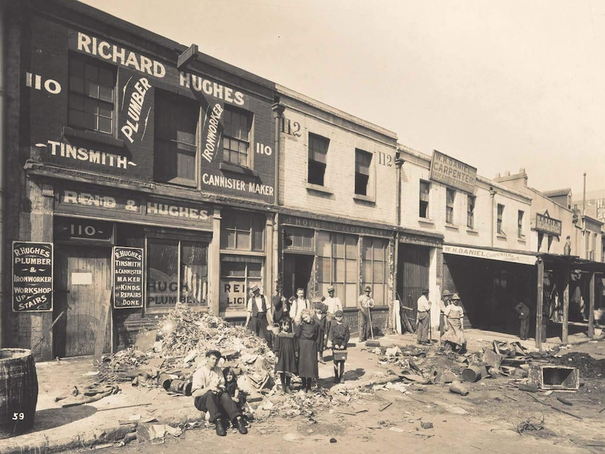 Sepia-toned image of people standing alongside debris in the street