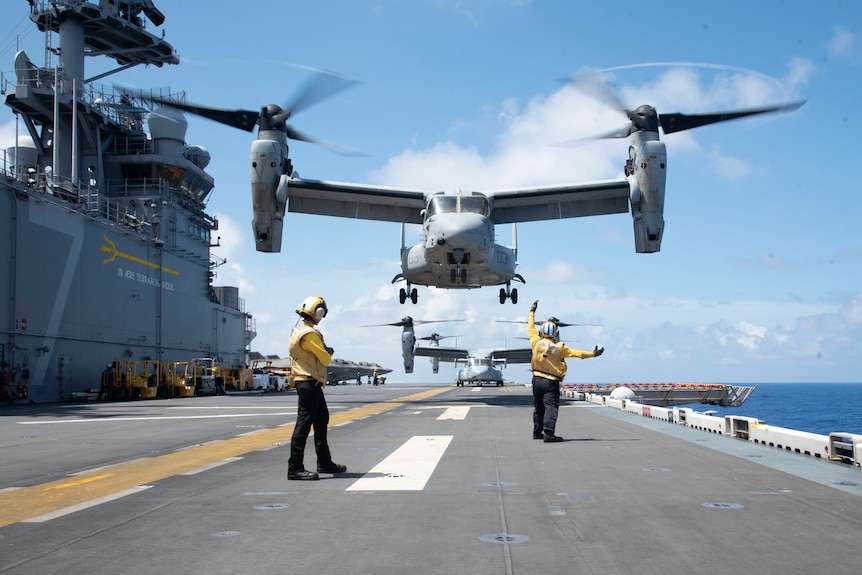 Osprey military aircraft taking off from landing helicopter assault vessel.