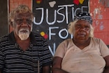 Eddie and Lottie Robertson sitting in front of a red wall with a sign reading Justice for Walker in the background