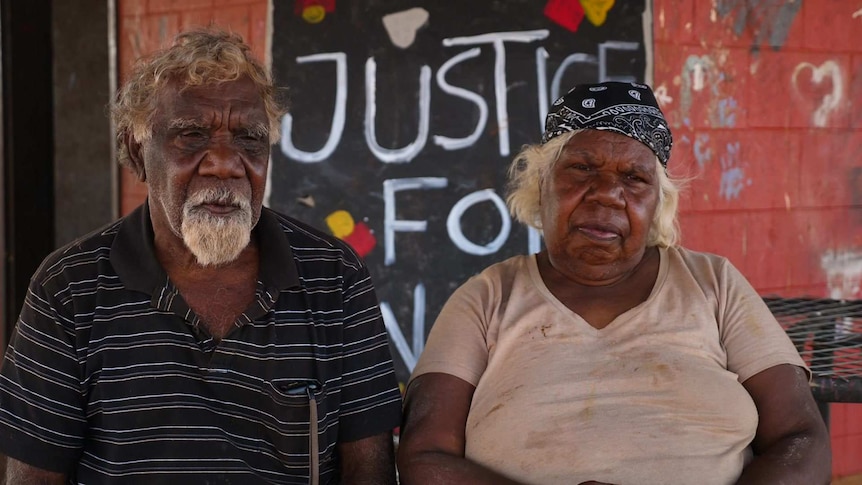 Eddie and Lottie Robertson sitting in front of a red wall with a sign reading Justice for Walker in the background