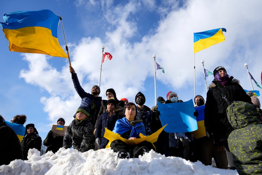 People wave Ukrainian flags at a protest in Ottawa, Canada.