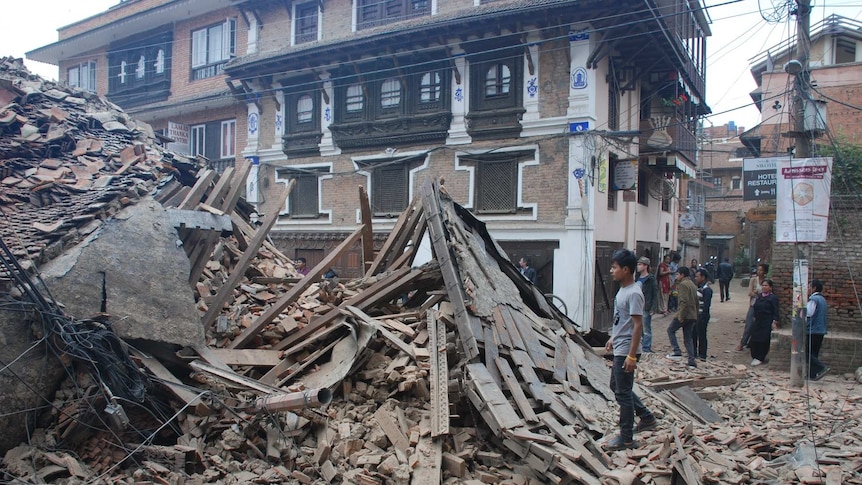 People look at collapsed buildings in Kathmandu