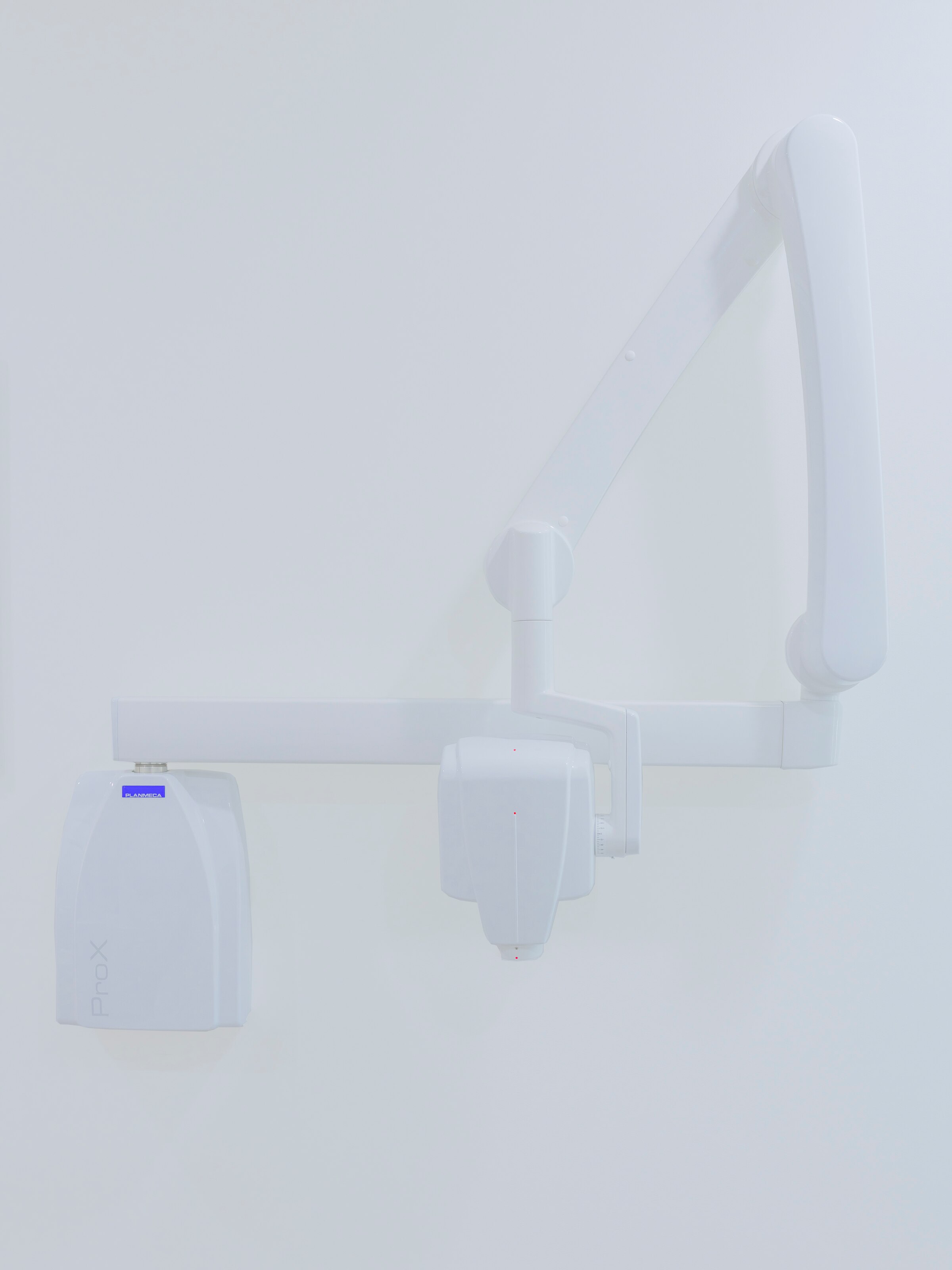 Photo of a white dentist's X-ray machine against a white wall.