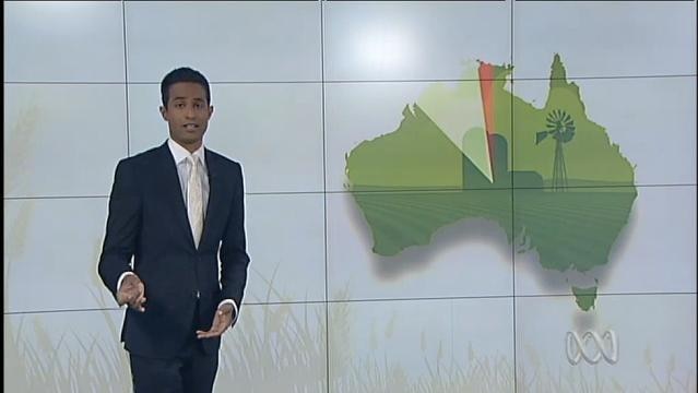 ABC Presenter Jeremy Fernandez stands in front of map of Australia