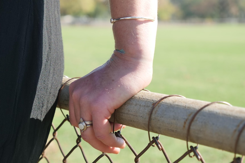 A close-up photo of a hand resting on a fence