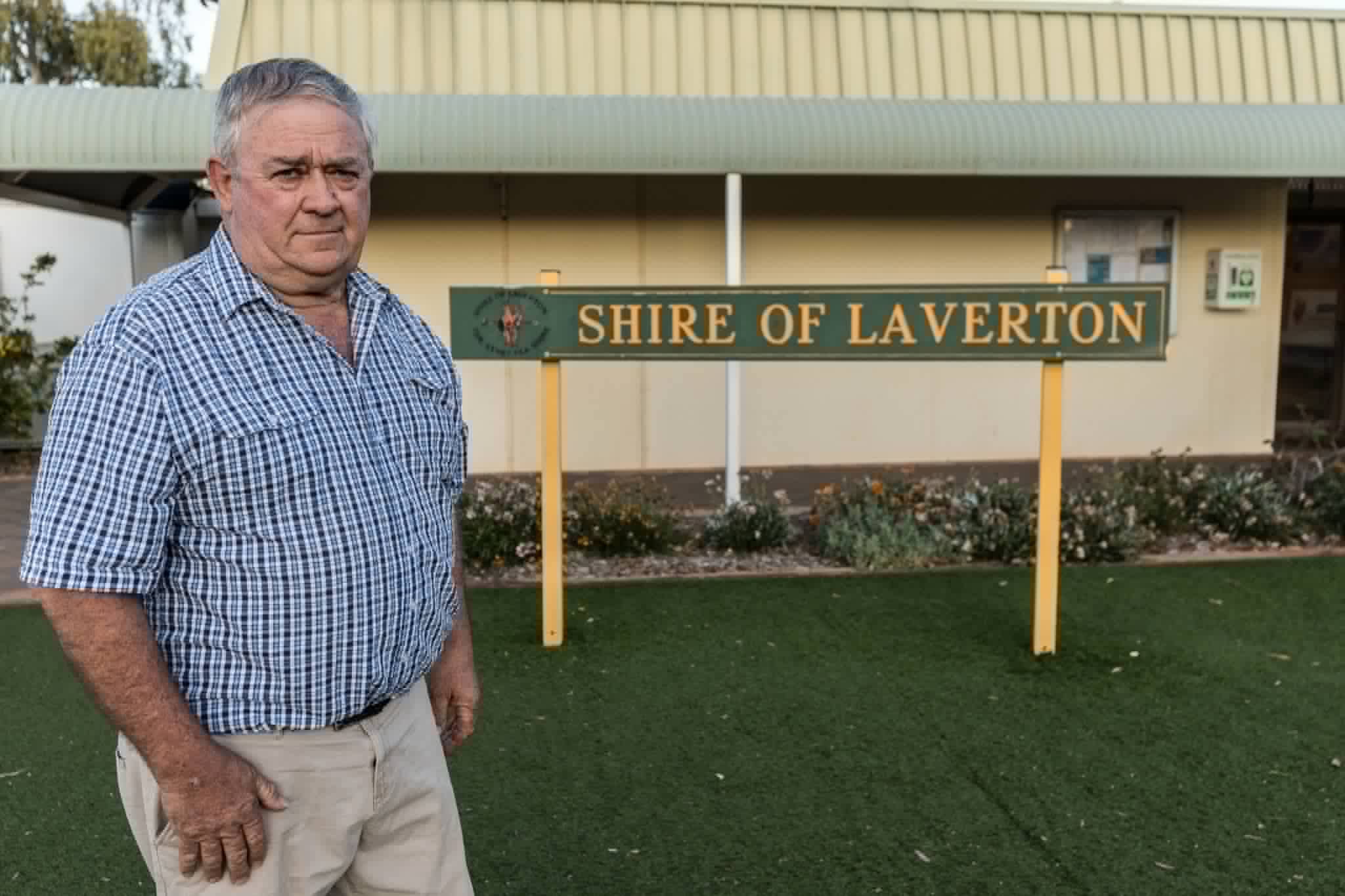 A man standing in front of a sign outside local council office.