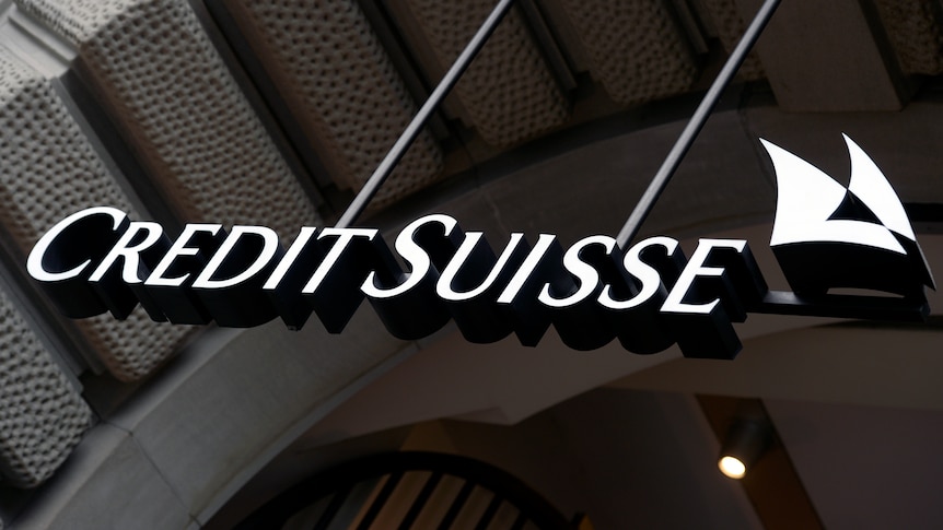 The Credit Suisse logo, which are the words in white on a glossy black building wall.
