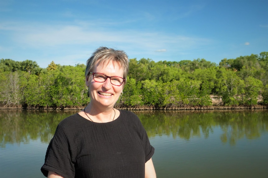 A woman leaning on a railing overlooking a mangrove creek.