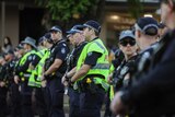 Queensland police officers stand in a line across a street.