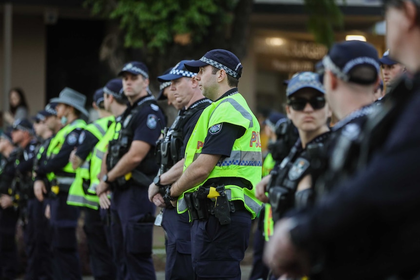 Police officers stand in a line across a street.