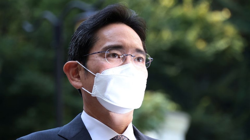A man with short black hair wearing a white face mask outdoors