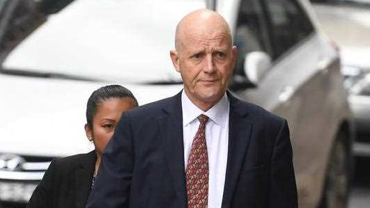 David Leyonhjelm, wearing a suit and tie, walks along a footpath.