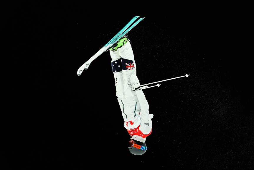 An Australian freestyle skier hangs upside down in mid-air as he makes a run in the final 1 of the men's moguls in Beijing.