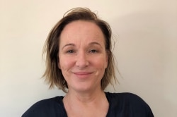 A close up of Rosie Sandover wearing a black shirt in front of a beige wall.