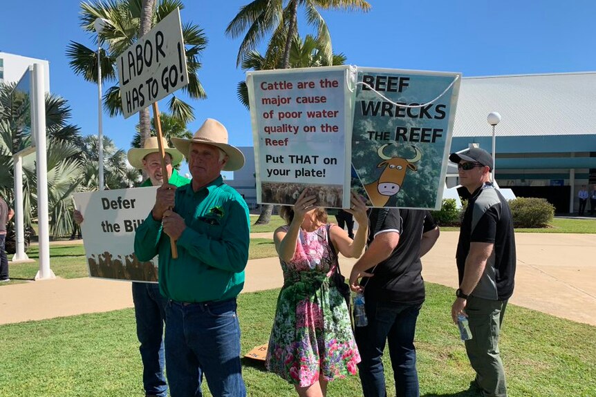 Protesters and counter-protesters wave placards on a sunny day in northern Queensland.