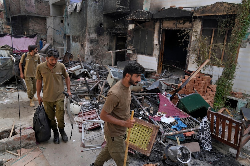Police officers walk through the rubble of homes  vandalized by an angry Muslim mob at a Christian area.