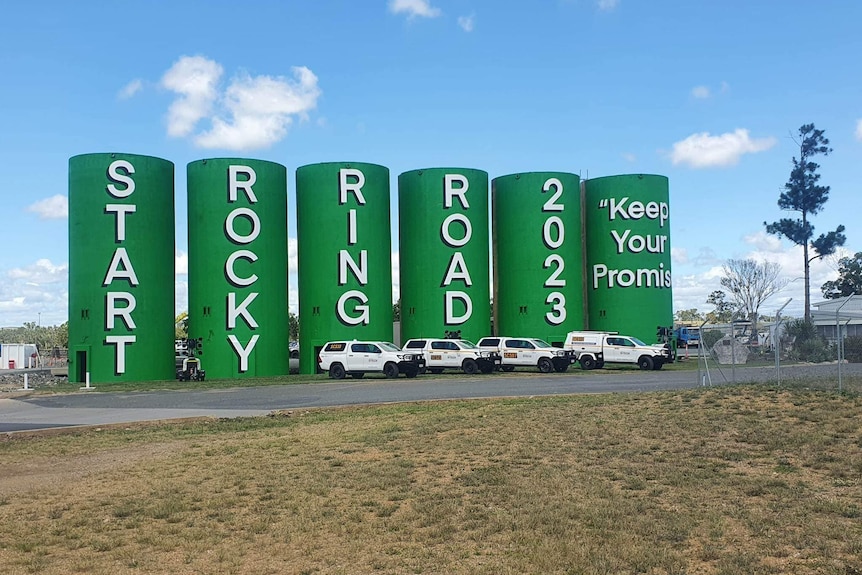 Six green silos stand beside each other and read "Start Rocky Ring Road Keep your promises".