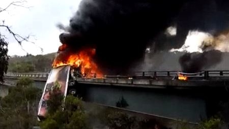 Truck on fire hanging over the bridge.