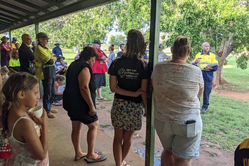 People in Fitzroy Crossing crowd around to hear from an authority about evacuation plans.