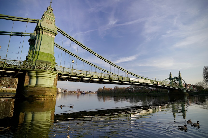 A steel suspension bridge spans the Thames River in London.