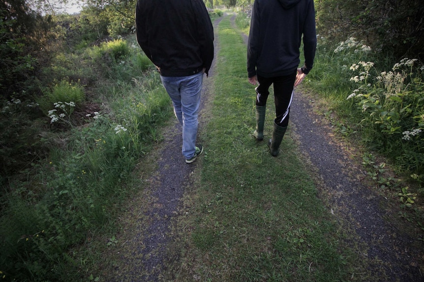 Two figures walk down a rutted road in Sweden