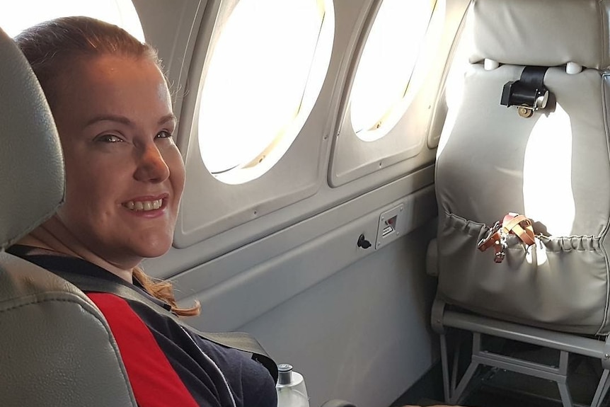 A woman with a guide dog inside a plane.