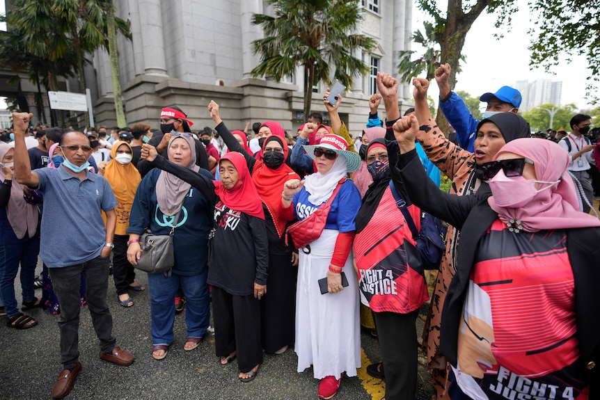 Los partidarios del ex primer ministro de Malasia, Najib Razak, usan máscaras y corean consignas fuera de la sala del tribunal.