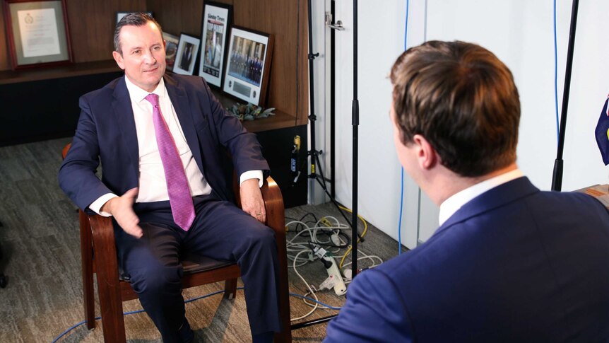 Mark McGowan sitting in a chair while being interviewed by a reporter.