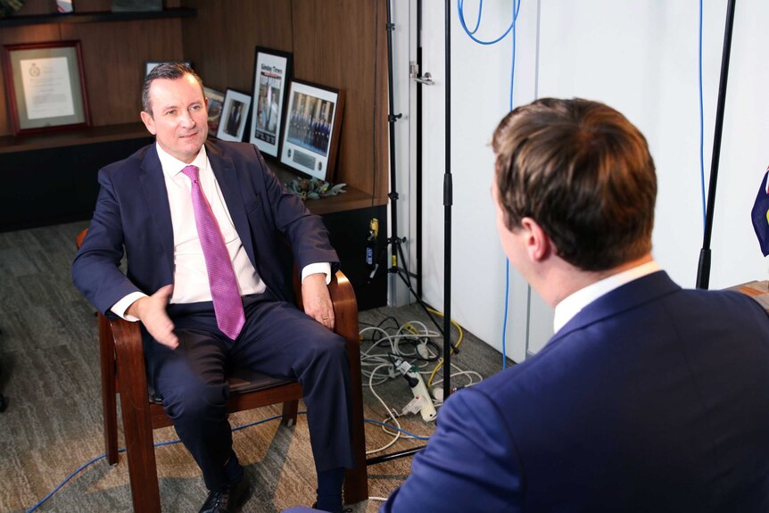 Mark McGowan sitting in a chair while being interviewed by a reporter.