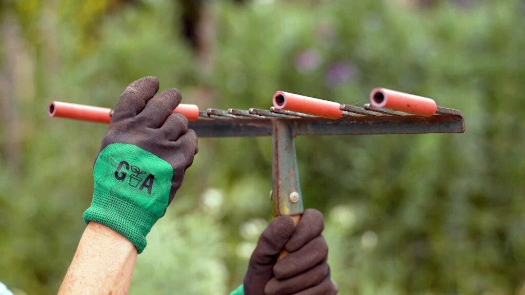 Plastic tubes being placed on the tines of a garden rake.