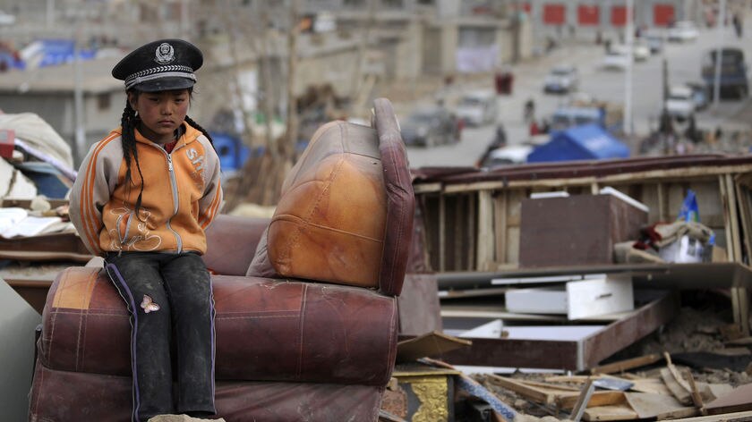 Girl rests amid earthquake devastation