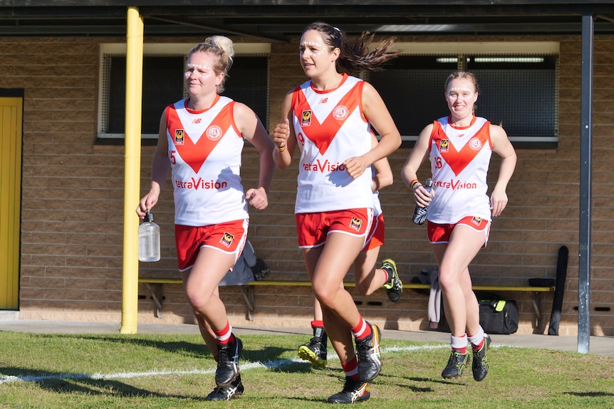 Three girls wearing sports jersey's emerge from changerooms