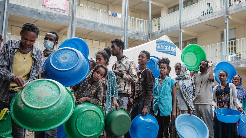 People who fled the violence in Ethiopia's Tigray region wait to receive food.
