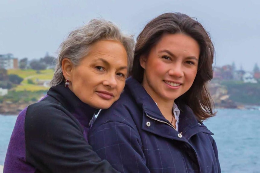 A woman and her adult daughter stand beside the water