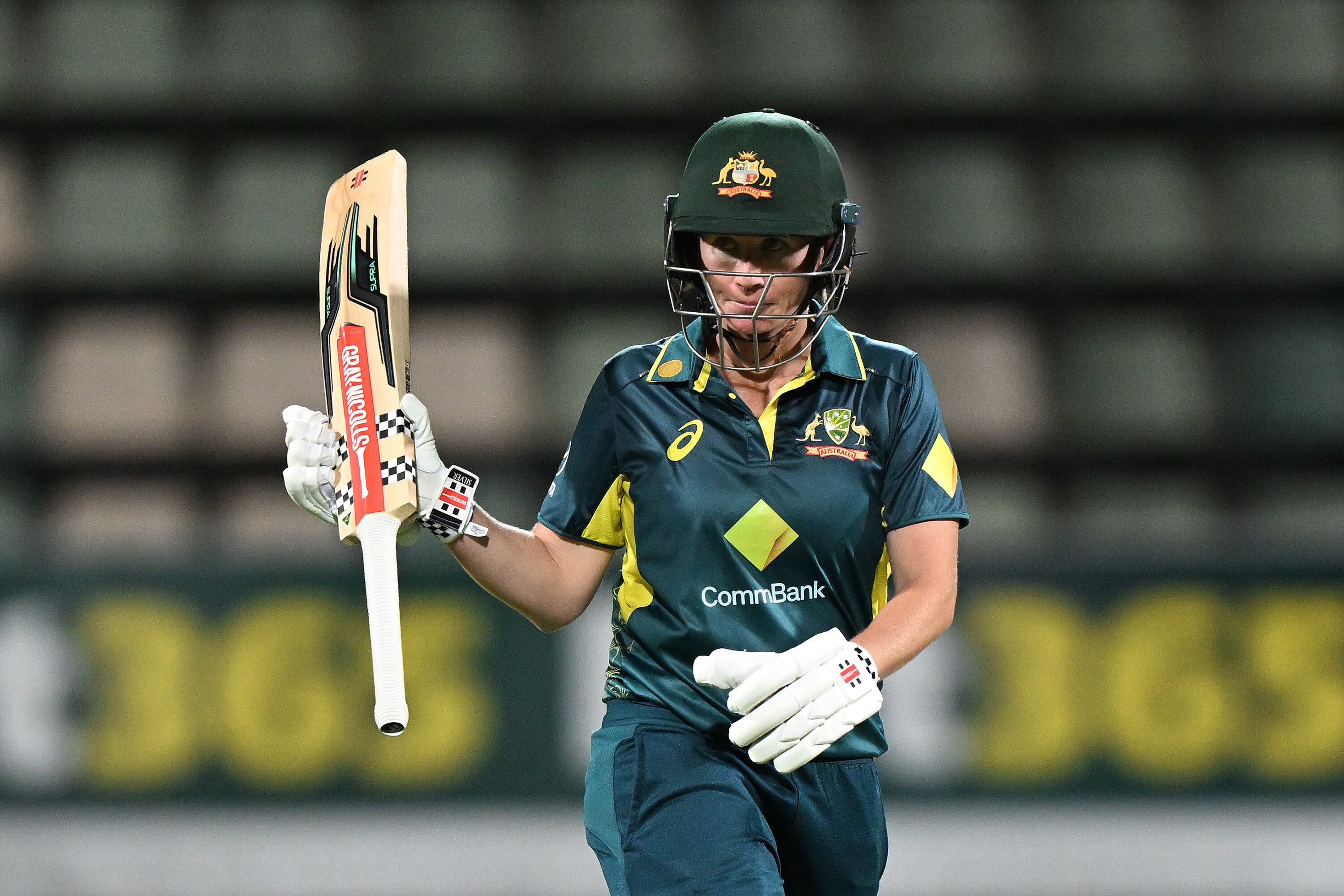 Beth Mooney raises her bat towards the crowd after reaching a half-century