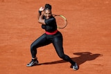 Serena Williams swings tennis racket on court.