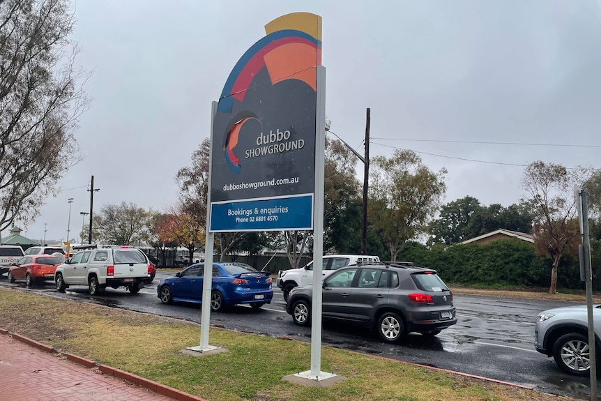 A "Dubbo Showground" sign with a queue of cars behind it