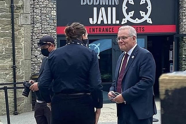 Scott Morrison is mid-conversation with a woman outside the main entrance to an old stone building.