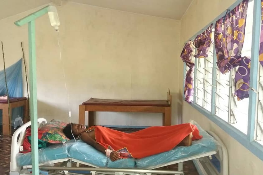 A young girl lies in a bed in a health clinic. 