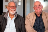 Two men in their 70s sitting side by side and smiling