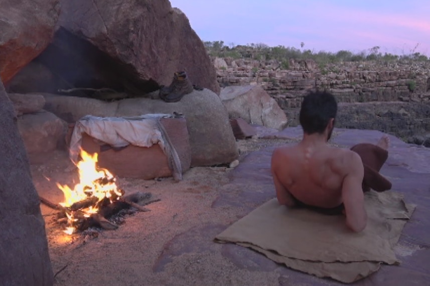 Mike Atkinson watches the sunset beside a campfire.